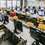 Ein Professor und Studierende sitzen in einem Hörsaal an Computern